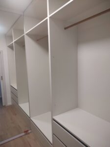 Šatna na míru s dřevěnými tyčemi na věšení a zásuvkami – realizace rodinného domu BMB